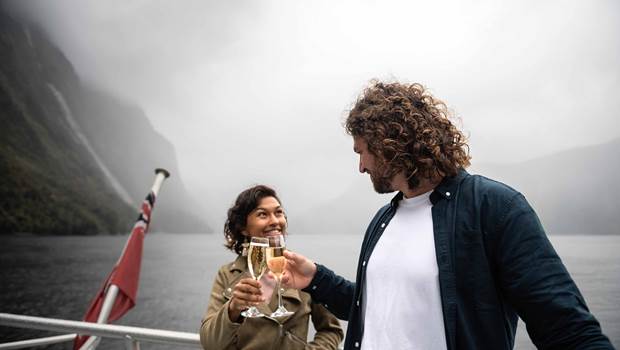 A couple cheers a glass of champaign on board the premium cruise in Milford Sound
